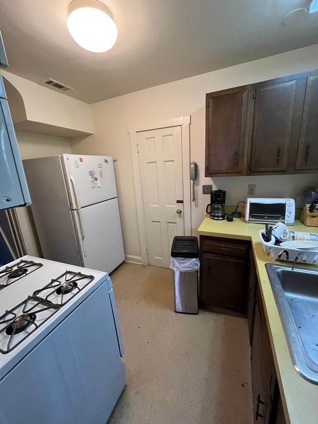 a small kitchen area with a stove, refrigerator, cabinets, and a sink