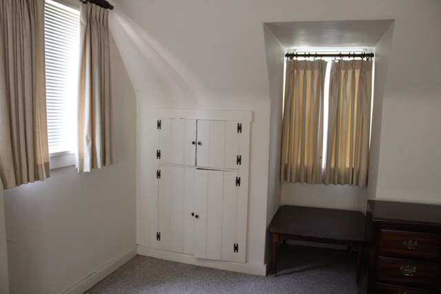 a corner of a bedroom that shows two windows and an in-wall cabinet