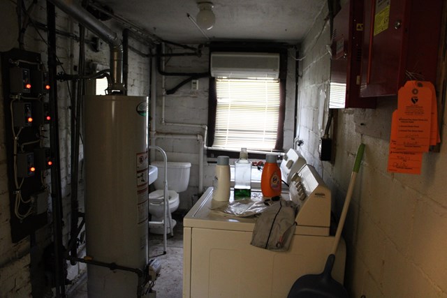 a dimly lit room with a water heater, electrical panel, fire panel, and washer and dryer