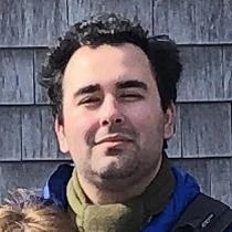 A group photo in front of an old wooden building of 16 HPC crew members and two HPC leaders. All are wearing cold-weather clothes, and most have the SCA logo visible on their hats or sweatshirts.