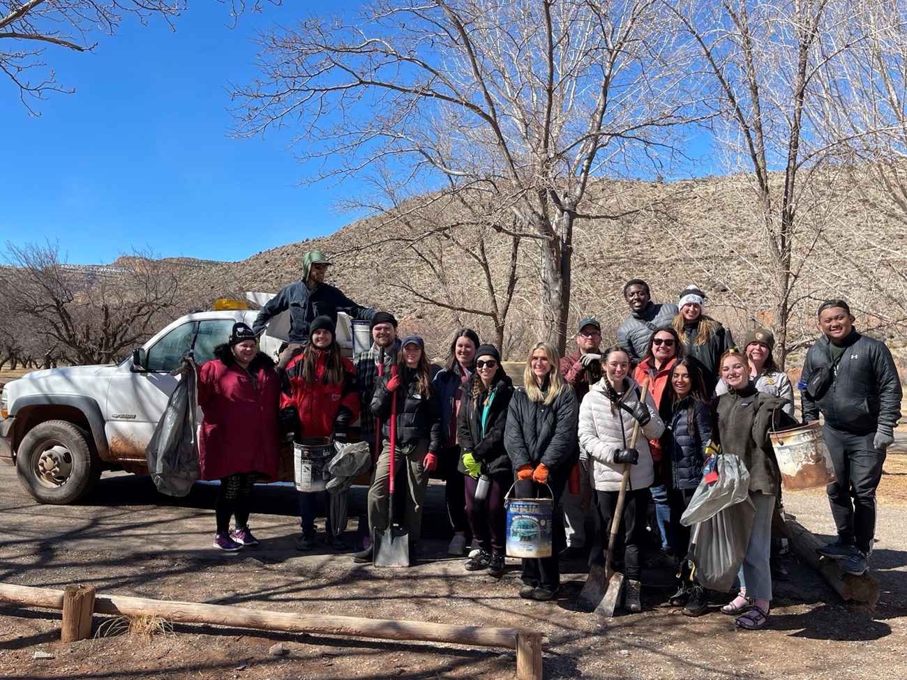 A group of volunteers dressed for winter stand in front of a white pickup truck