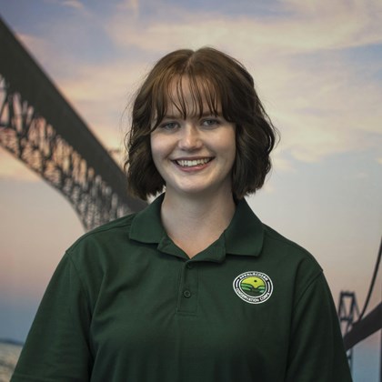 Headshot Photo of Shelby Phillips with a bridge and clouded sky background.