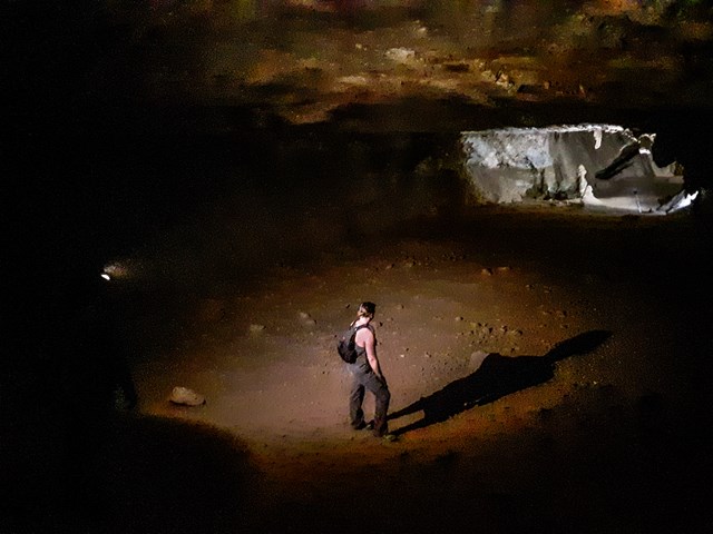 visitor looks at lit sub-room of the cave in many yards away