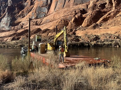 Construction workers on a barge at a river beach