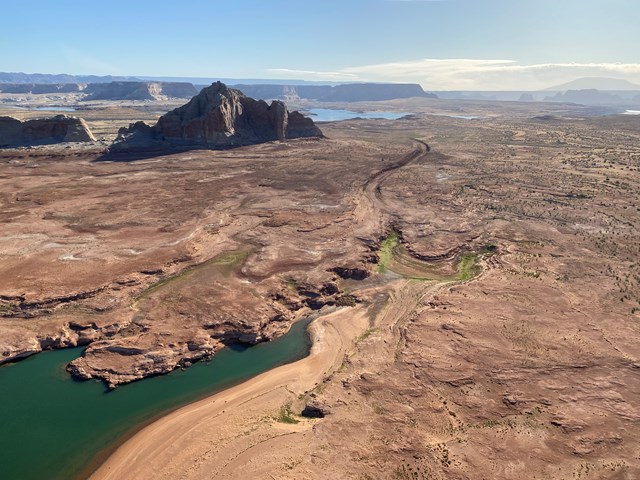 Aerial view of a desert lake against a sandstone canyon with grooves leading to the distance