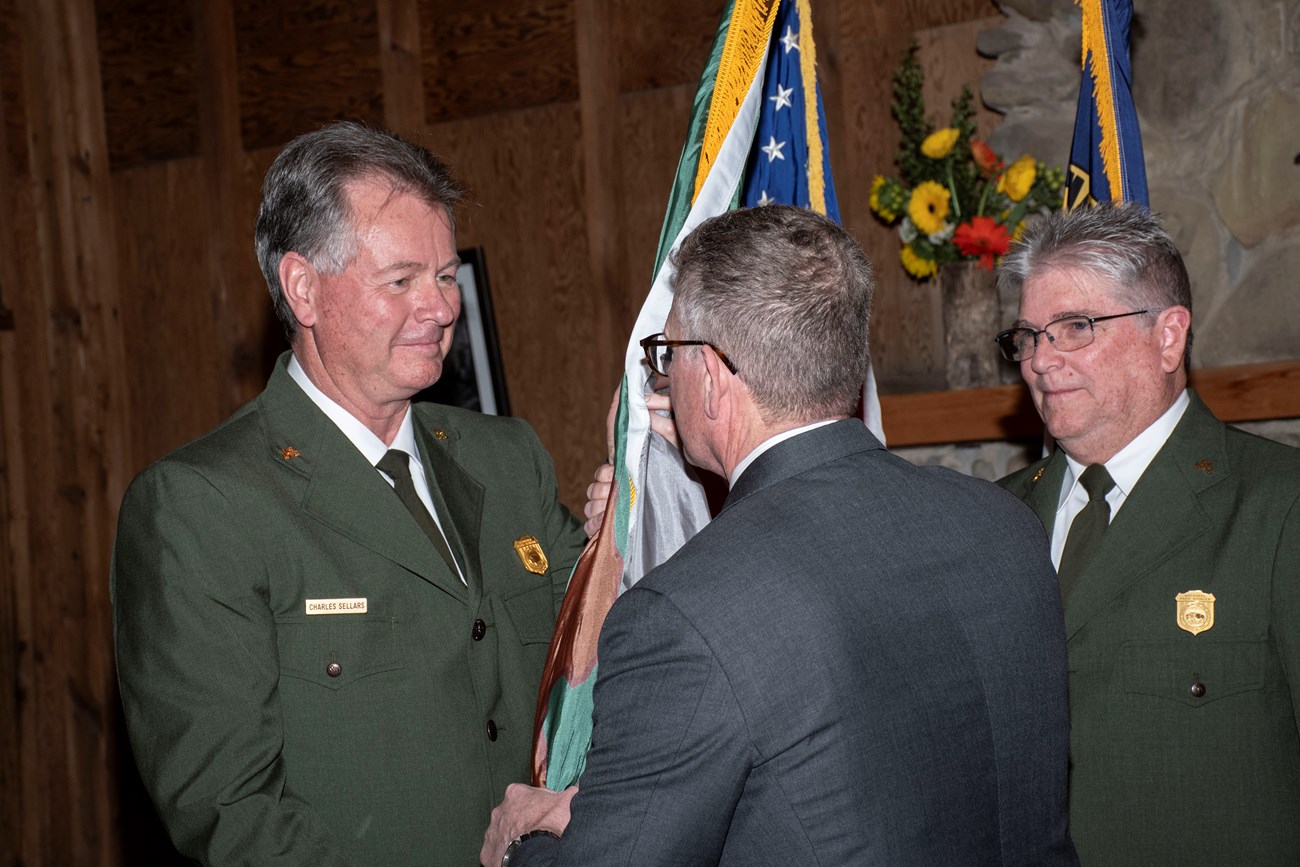 A ranger shakes hands with a person in a suit.