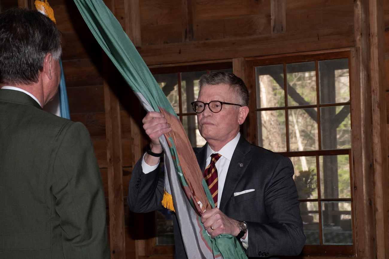 A man in a suit holds a flag in his hands.