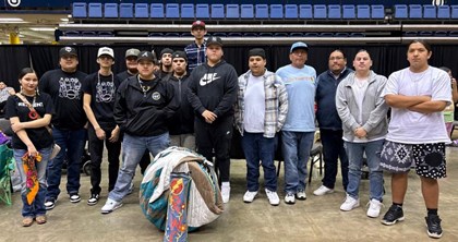 14 individuals look into the camera. 10 wear hats, and all appear to be Native Americans.