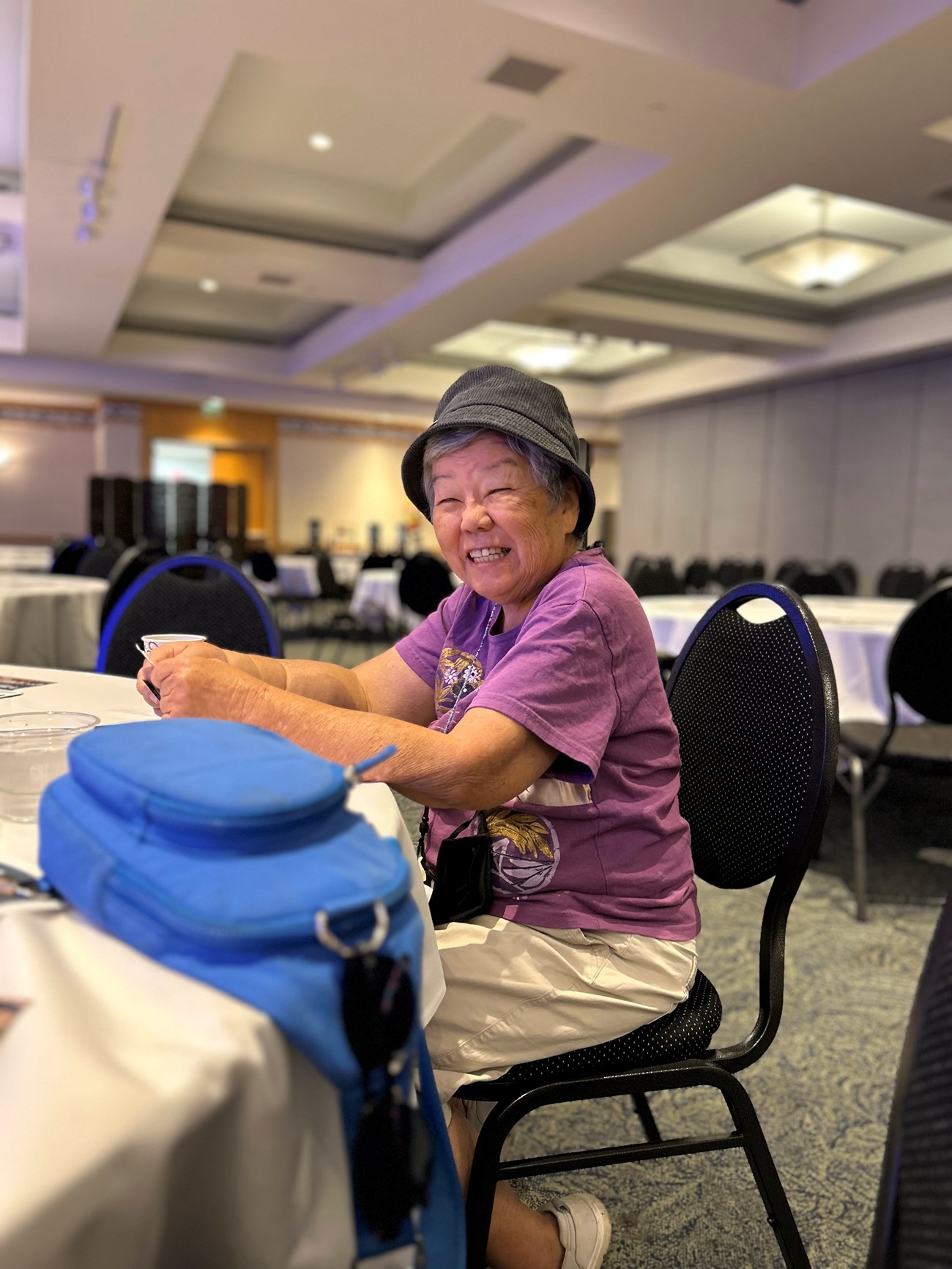 An elderly woman sitting at a table smiling