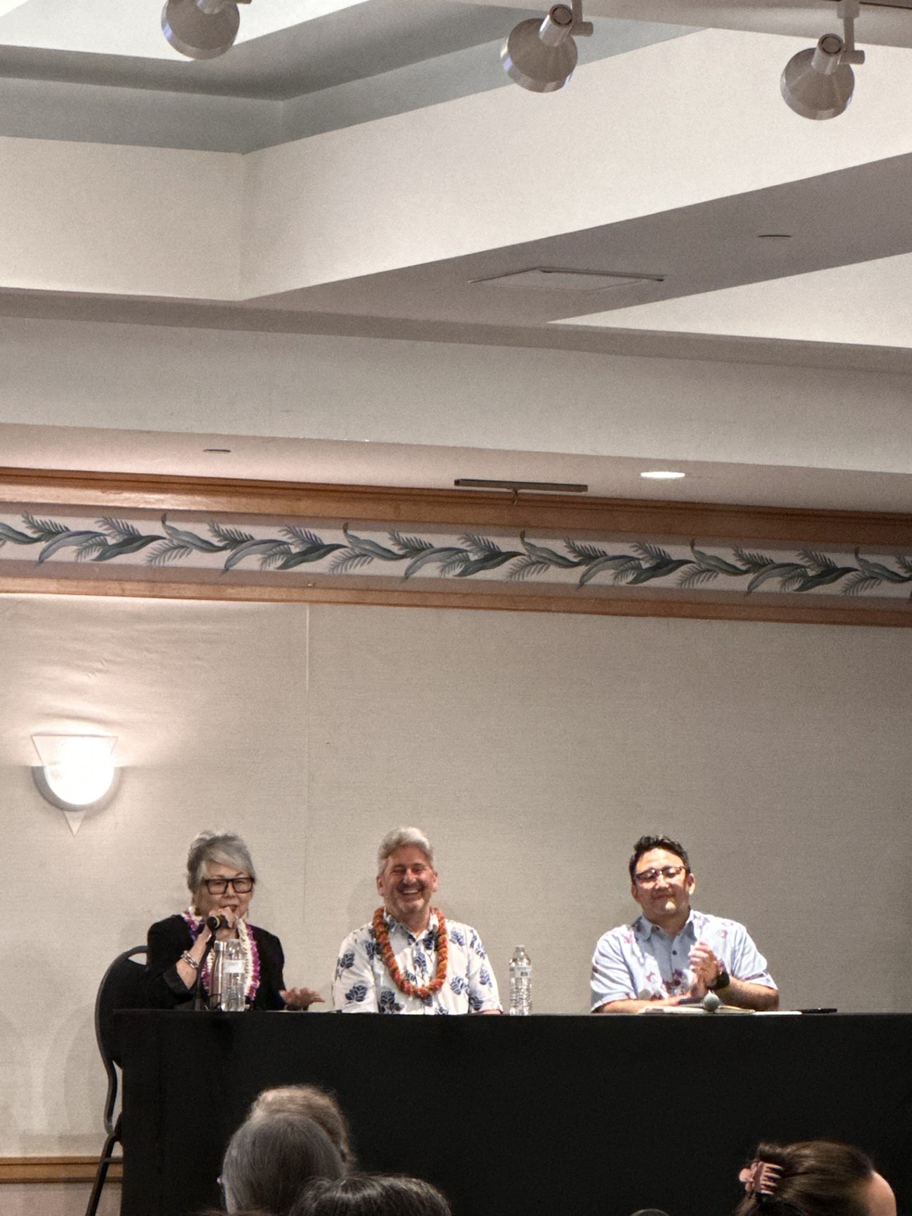 A woman and two men sitting on stage at a table.