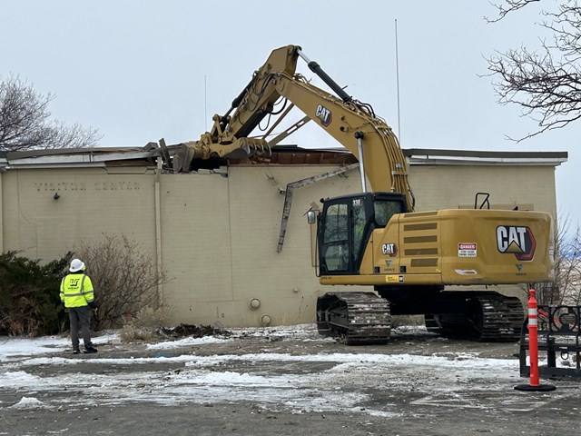 Large machine tears into a building wall. 