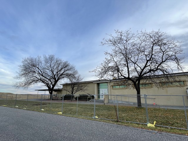 Picture of visitor center with chain-link fence around it. 