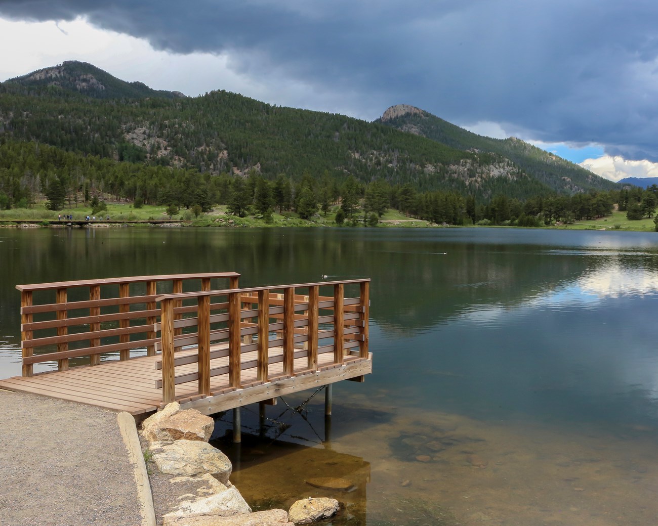 Small dock one top of a lake with mountains.