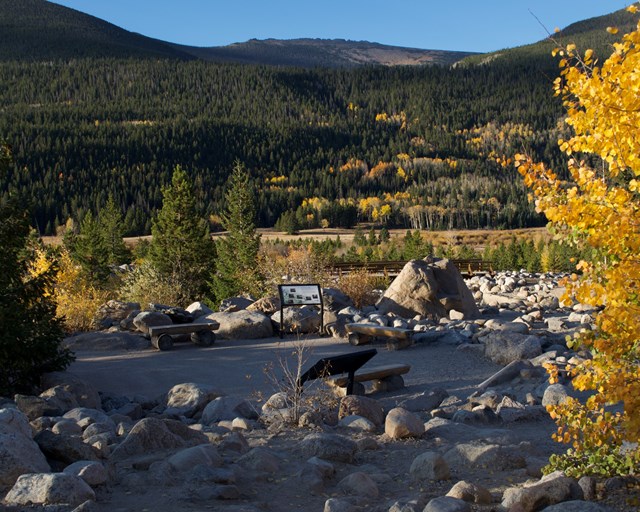 Small paved platform surrounded by rocks, trees, and mountains.