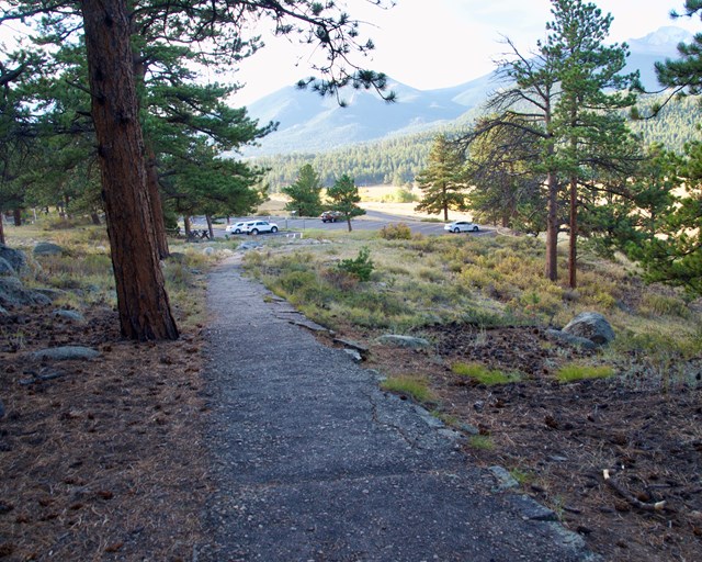 Partially paved path going uphill from parking lot.