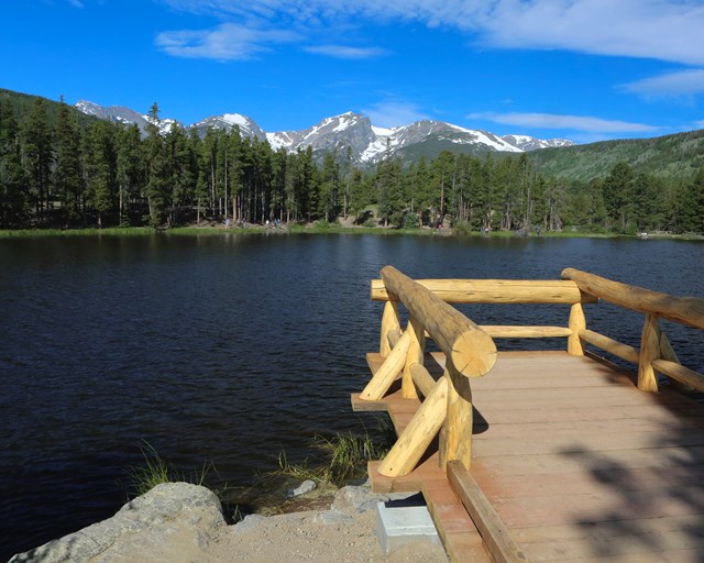 Wood dock on a lake with mountains.