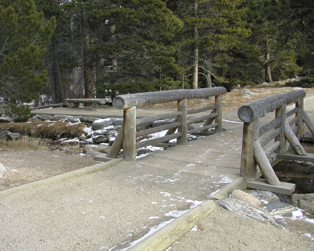 Wooden footbridge on a path with a sprinking of snow.