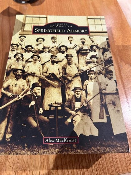 Picture of book cover showing men holding model 1873 rifle in various stages of completion. 