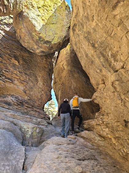 hikers under huge rock arch