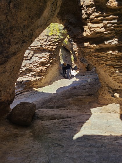 hikers hike up a tunnel-like rock formation