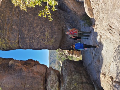 hikers standing in front narrow gap in 2 high rocks