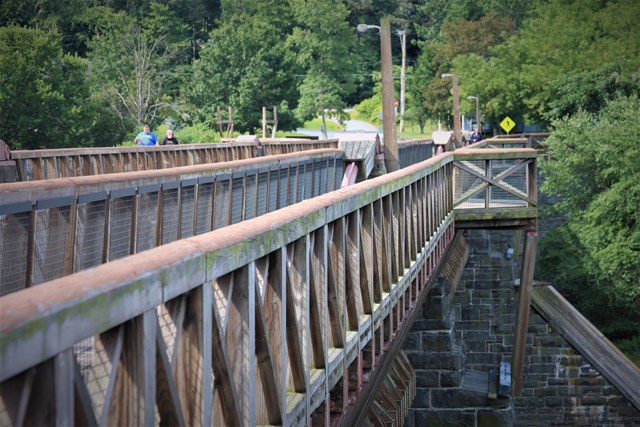 Walkways on both sides of bridge with chest-high wooden fencing/railing and overlook areas.