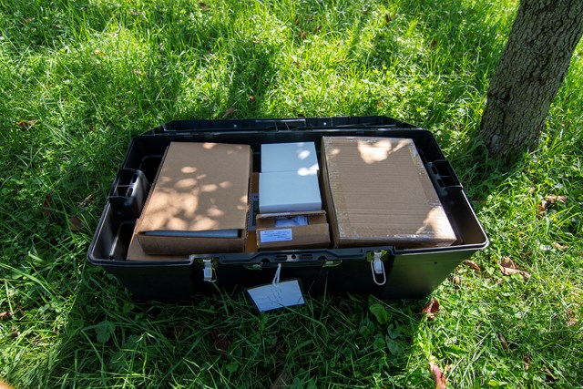 black plastic trunk with the lid open to reveal tightly packed cardboard boxes