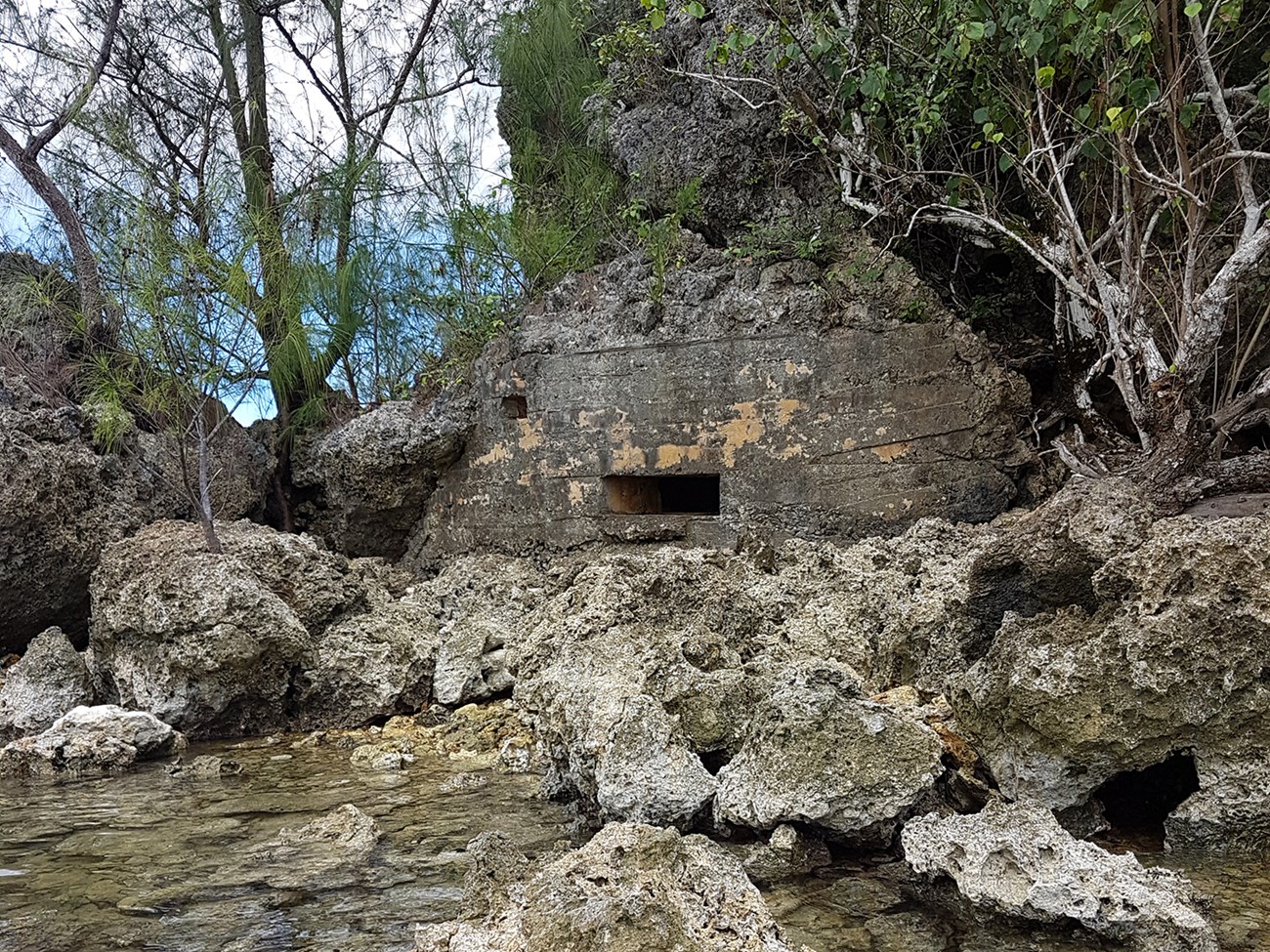 A concrete bunker build into a rock cliff with two openings.