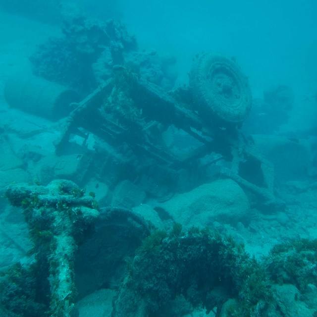 A upside down jeep underwater covered in coral.