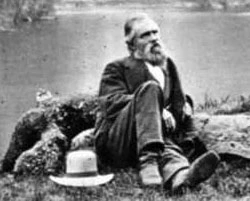 Black and white image of Galen Clark sitting near a river. 