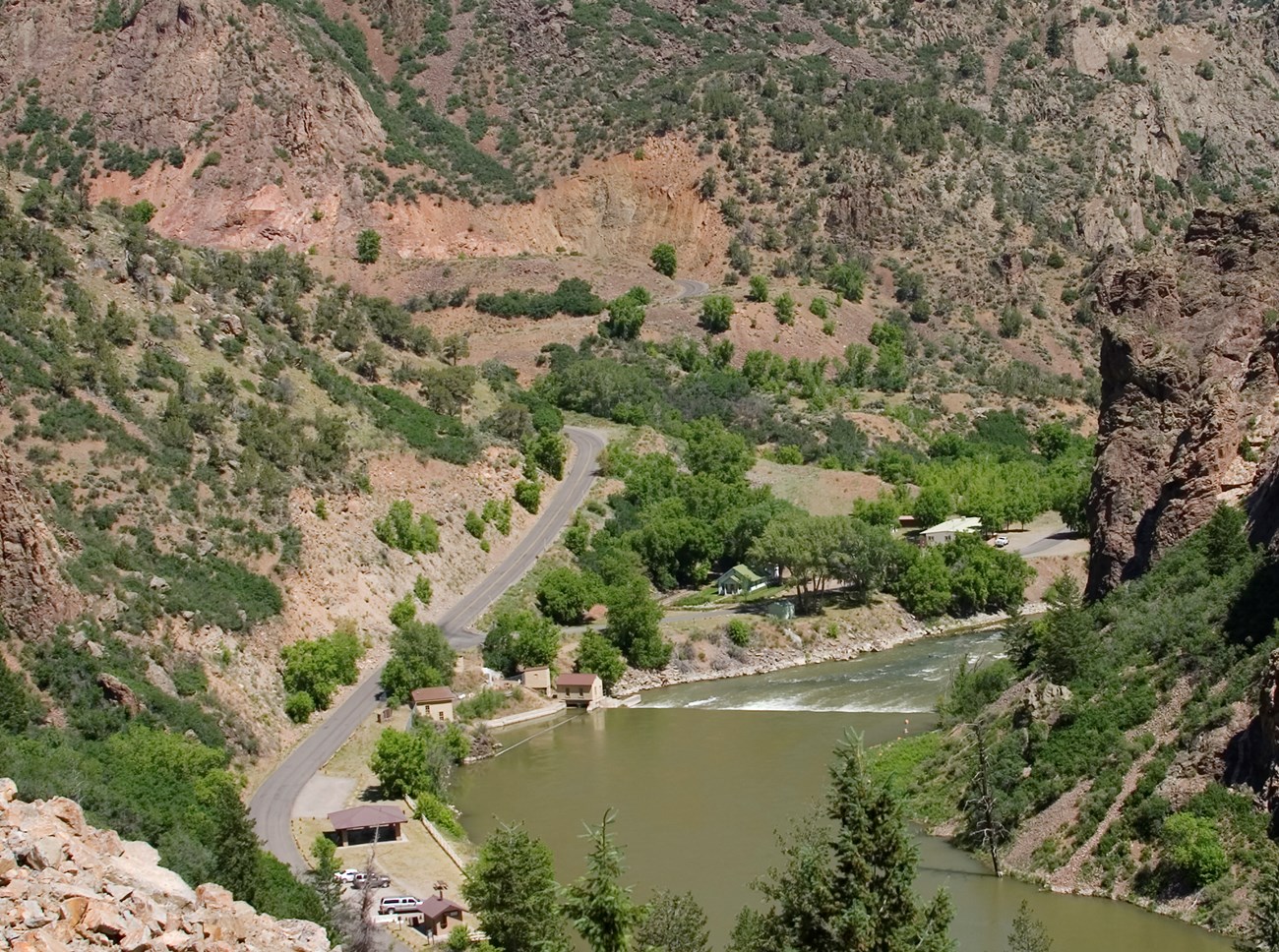 Historic black and white image of a town built alongside a river. Canyon walls rise on either side of the town. Buildings rise up the canyon walls and a power plant is right next to the river.