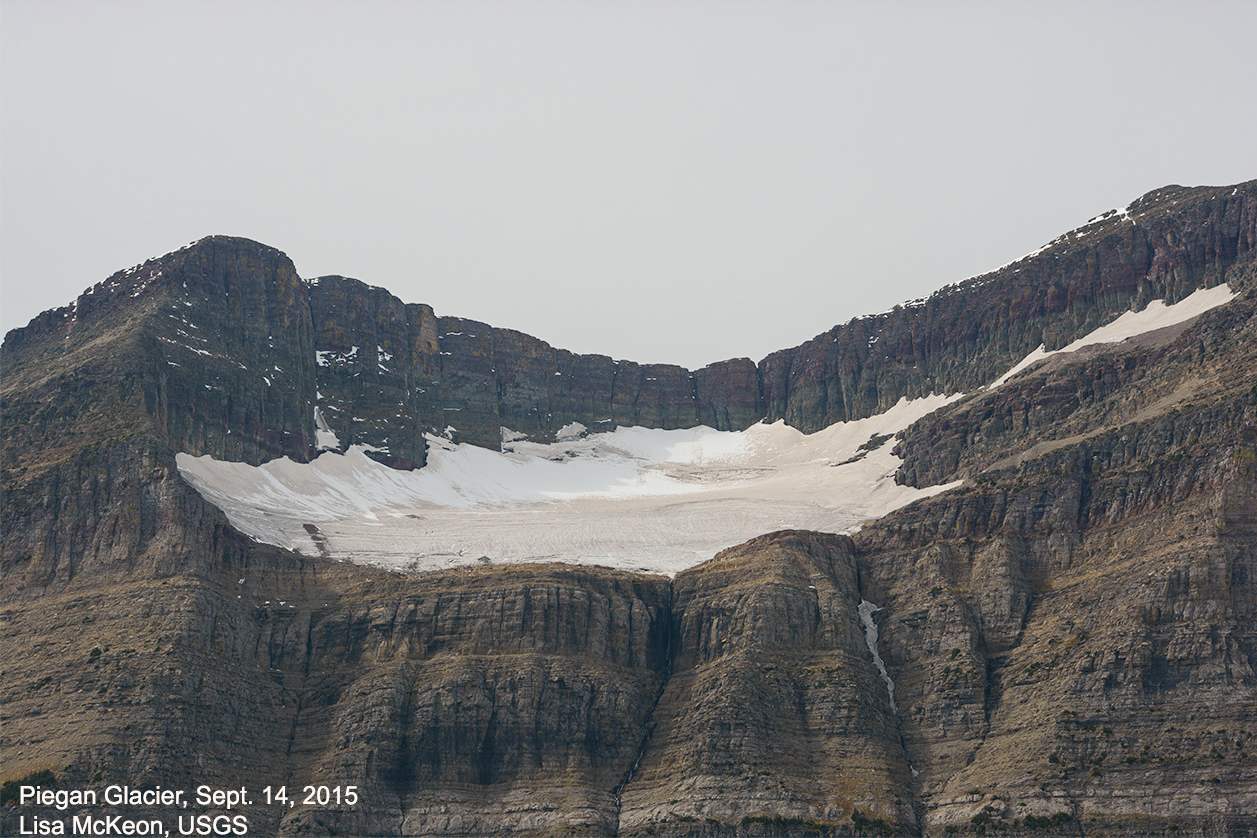 A cirque glacier in the center of an image with two mountain peaks rising up on each side.