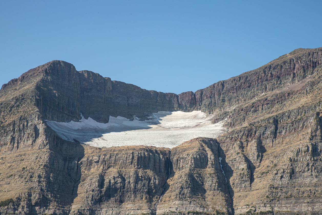 A cirque glacier in the center of an image with two mountain peaks rising up on each side.