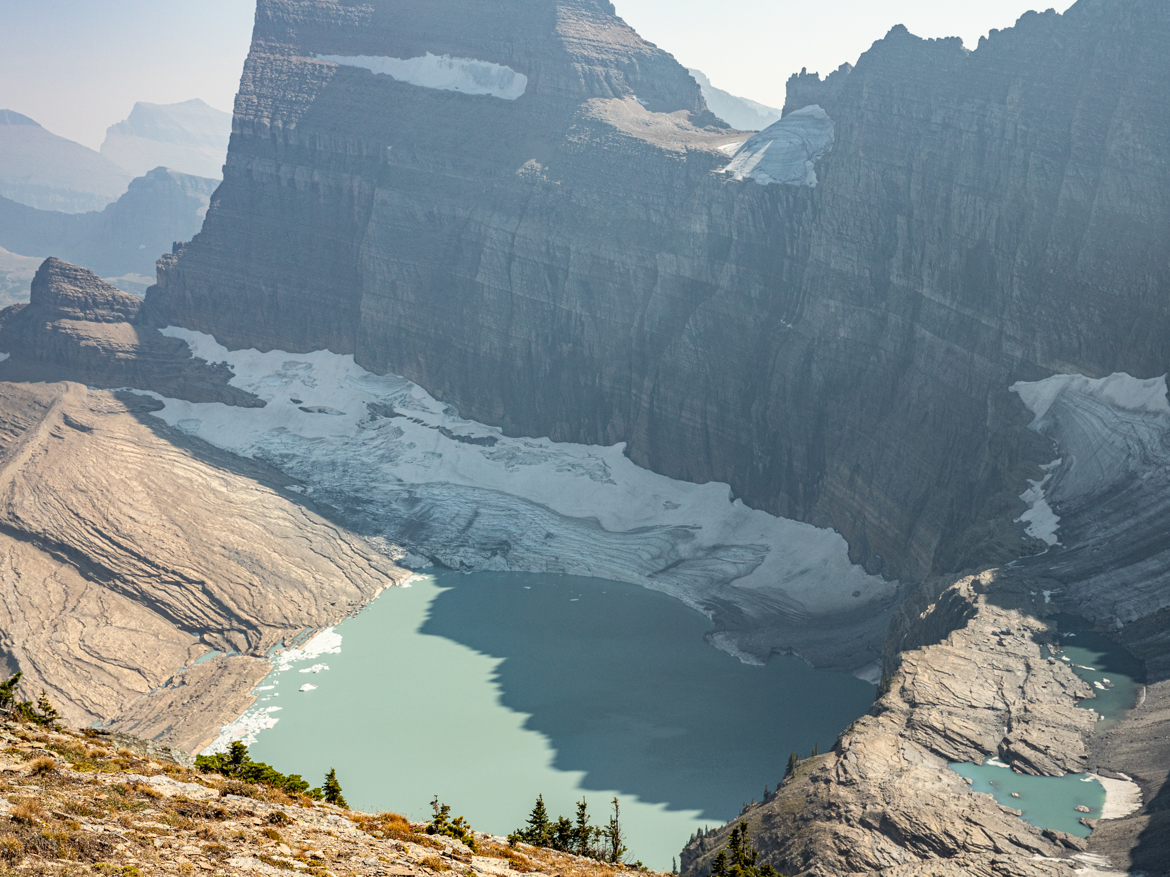 A mountain glacier tucked against a mountain with a lake forming at its front.