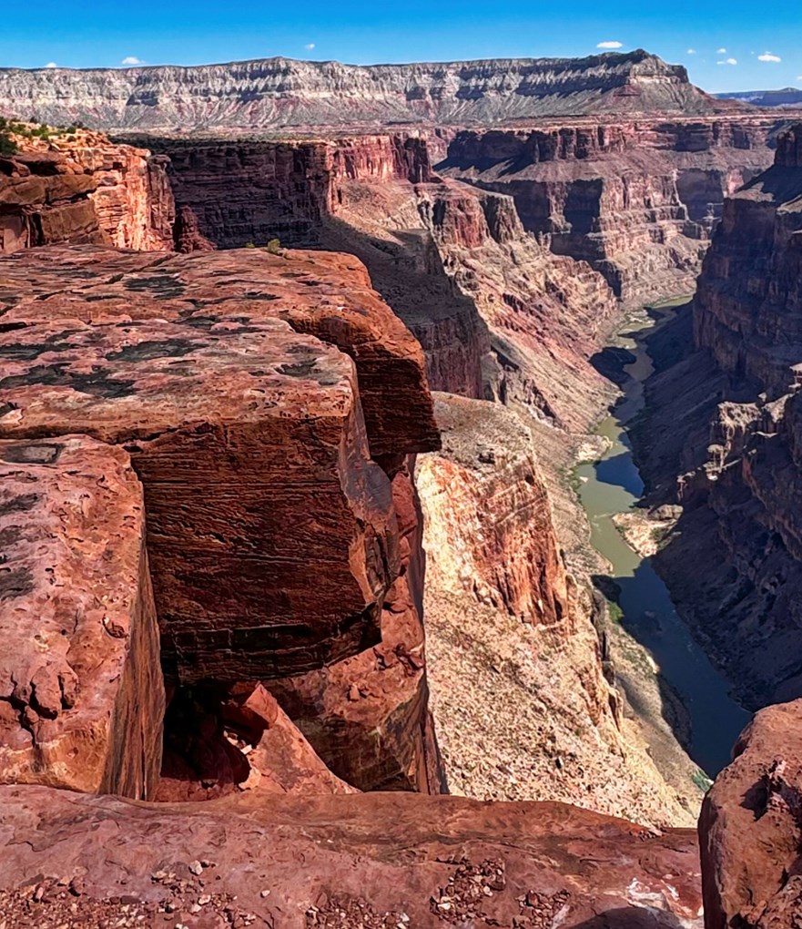 Two men on edge of cliff with river below.