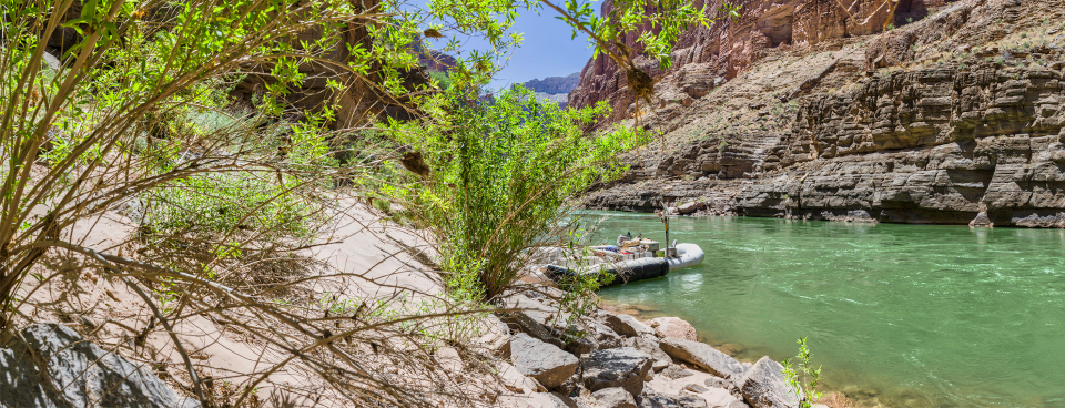 Men with boats on river bank with cliffs in background
