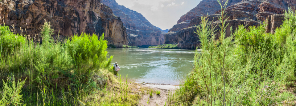 Men playing horseshoes next to river, cliffs in background