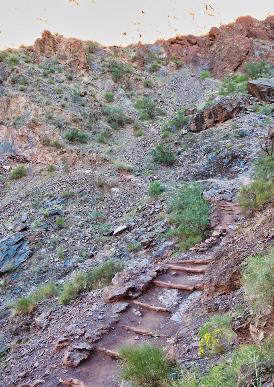 Men carrying cable down rocky trail and cliffs