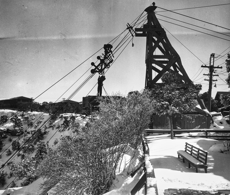 Tower with cables down into canyon.  Bench and snow on ground