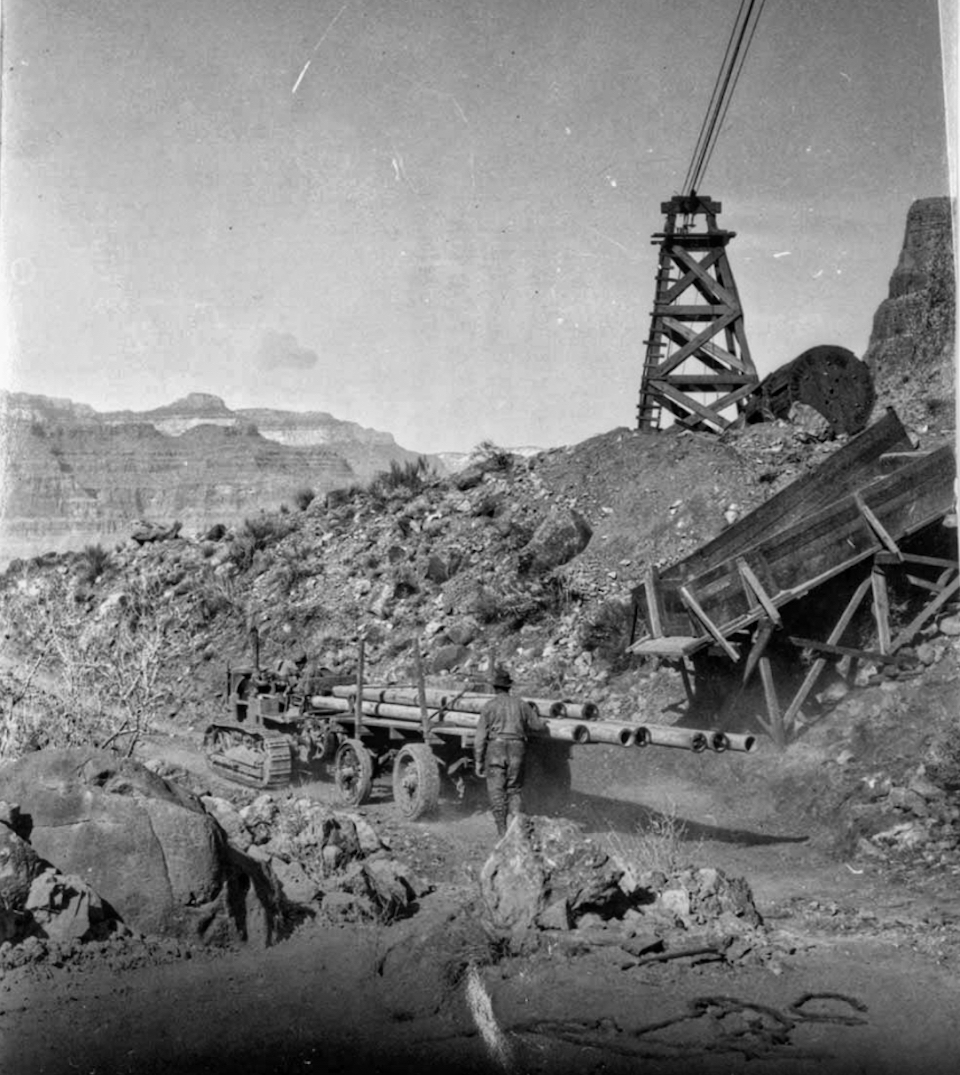 Tractor and building materials with tower and cable, mountains in background