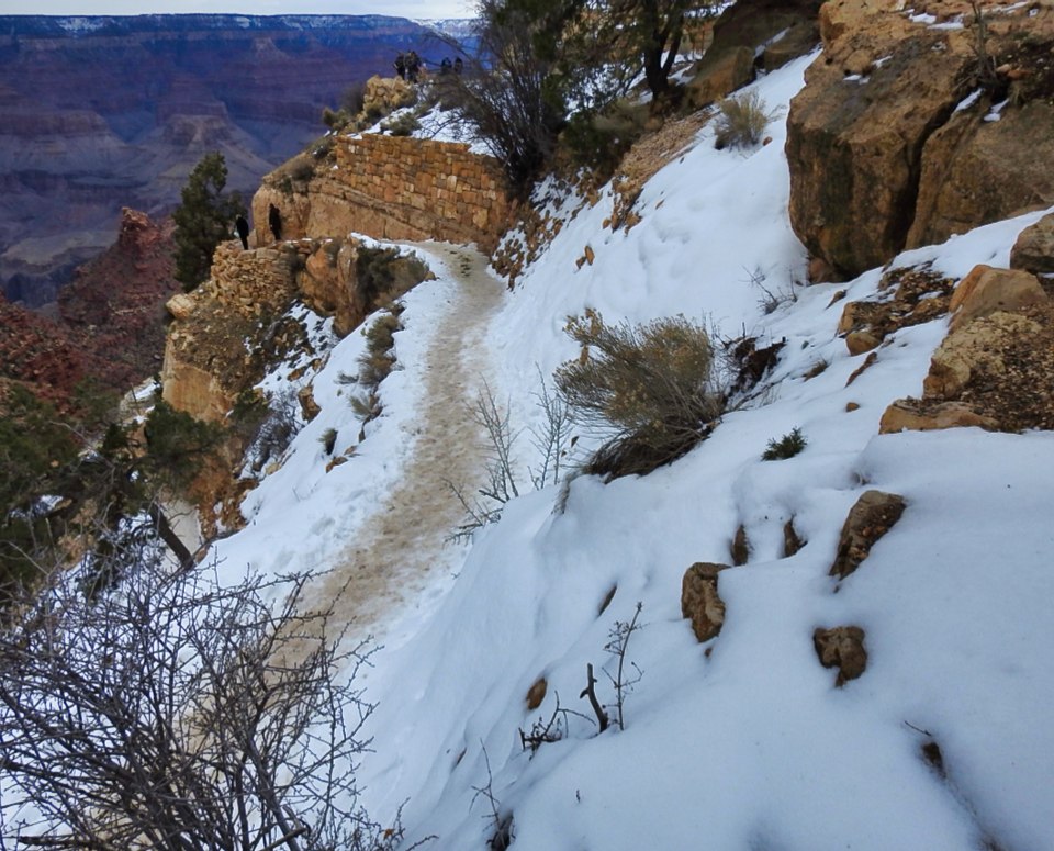 Men shoveling deep snow on slope with trees in background