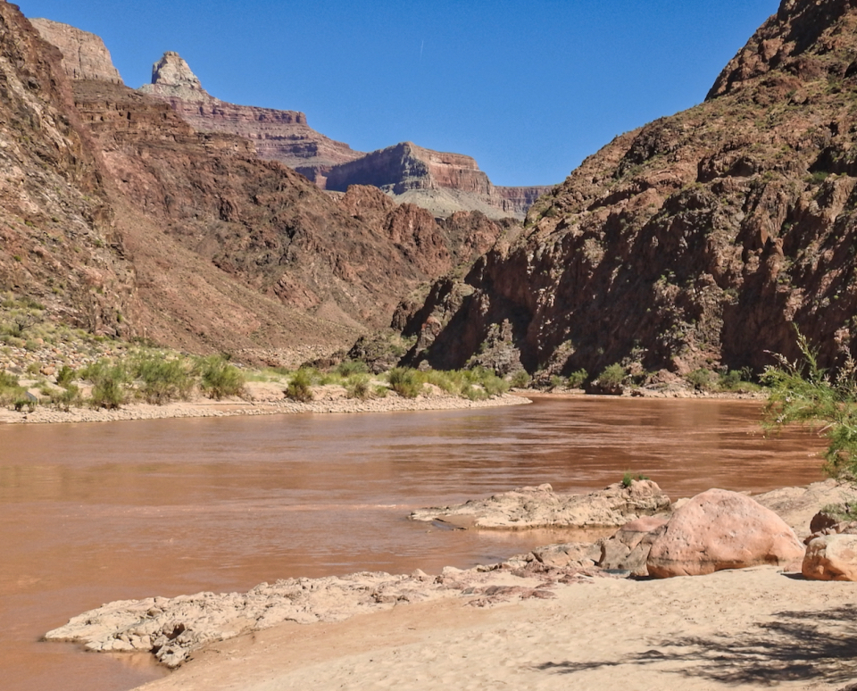 A group of people on the river beach with cliffs in background