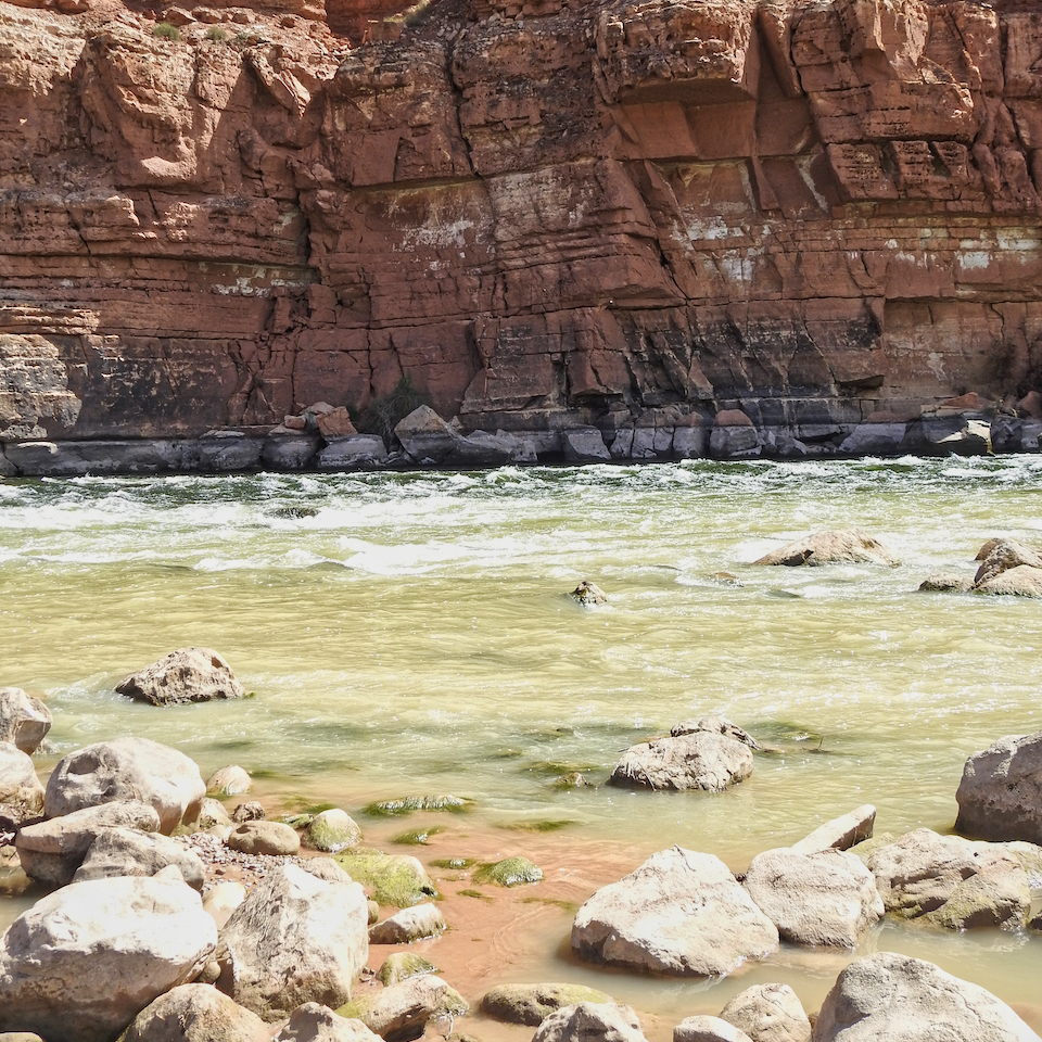 Woman standing on rocks in river with cliff in background