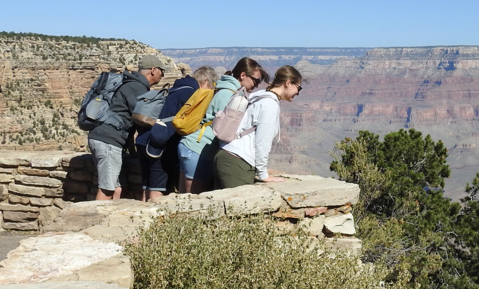 Old automobile on edge of cliff with man peering over edge