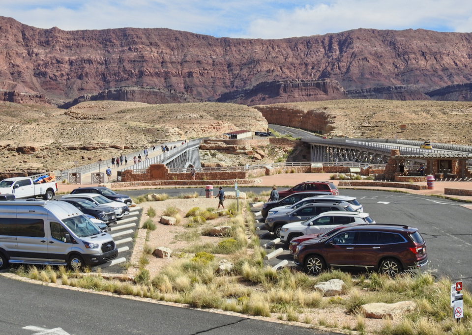 Large group of people with cars, bridge and hills in background