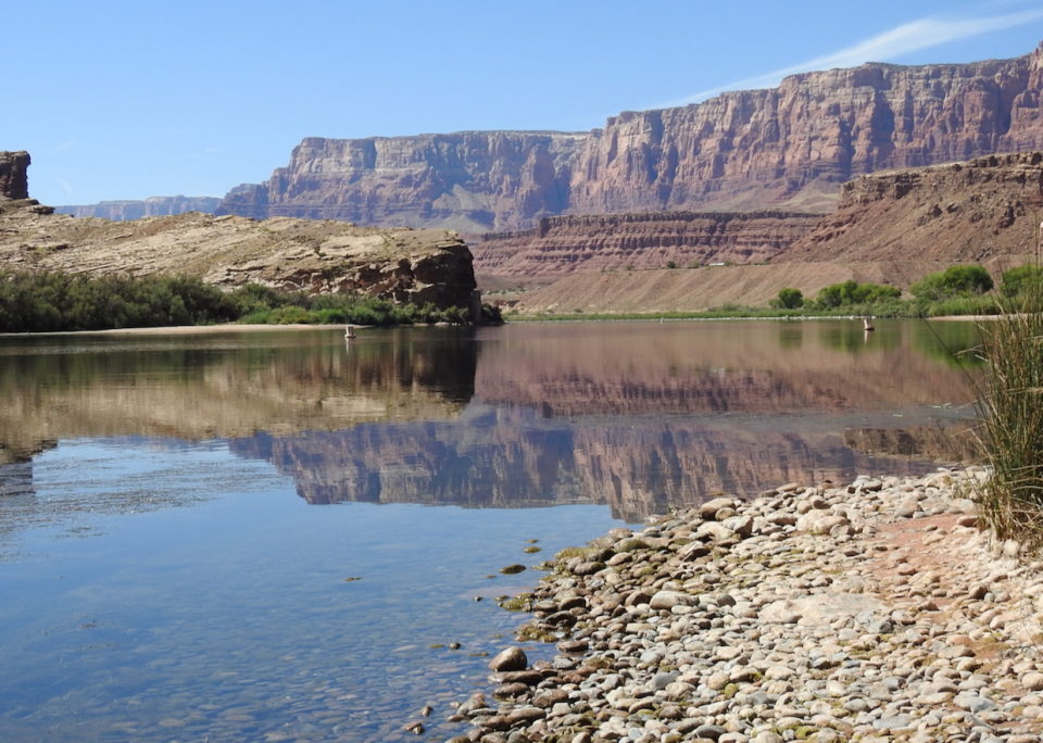 Men and women in a boat on a river with cliffs in the background