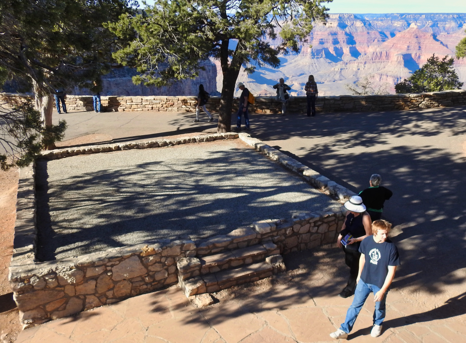 People in Native American ceremonial clothing dancing with others watching.