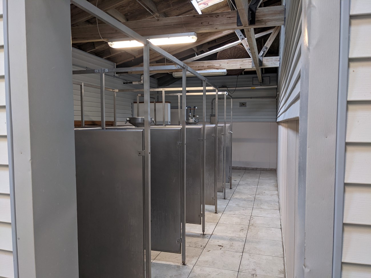 A shower room with metal dividers.