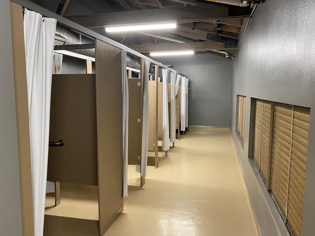 A shower room with metal dividers.