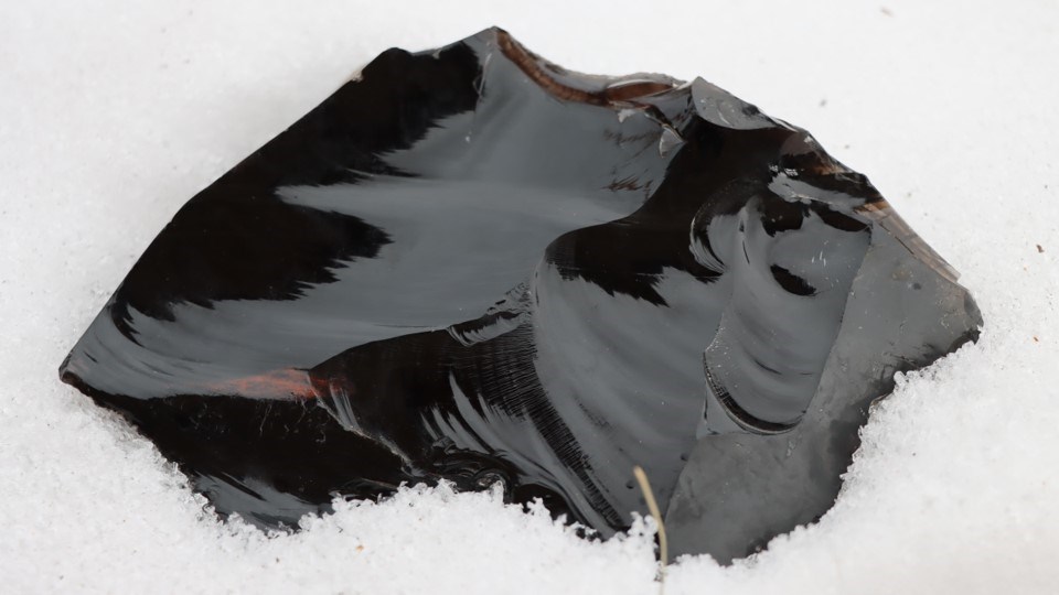 A piece of dark volcanic glass with the word "obsidian" over the image.